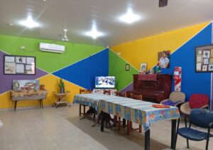 Salon comedor amplio con paredes color amarillo, verde y azul. Hay una mesa con mantel muy amplia y algunos cuadros colgados en la pared.