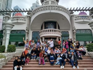 Grupo de personas sentadas sobre una escalera con niños y niñas en las piernas y a upa