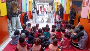 Grupo de niños y niñas sentados de espalda mirando a las maestras